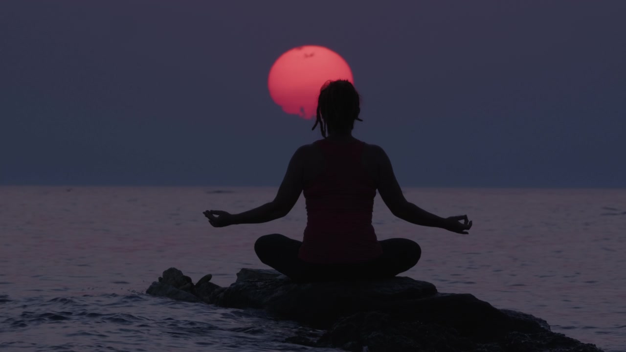 詳情圖-在令人驚嘆的日落天空和大太陽期間，坐在海水中的石頭上冥想的女人的剪影。治療身體，心理和精神狀態(tài)的人。