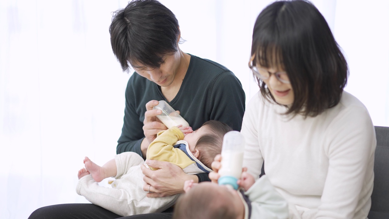 亚洲父母正在给双胞胎婴儿喂奶