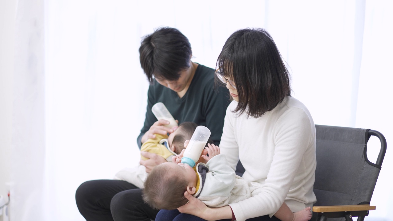 亚洲父母正在给双胞胎婴儿喂奶