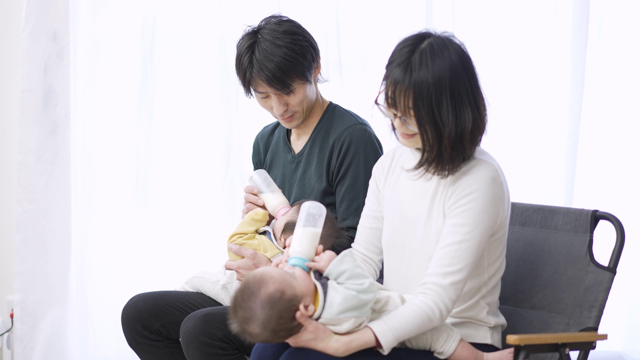 亚洲父母正在给双胞胎婴儿喂奶