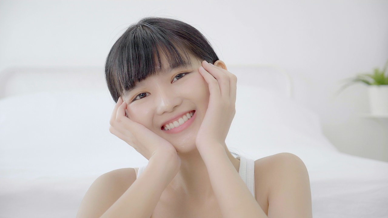 美丽年轻的亚洲女性化妆的化妆品，女孩的手触摸脸颊的脸和微笑吸引人，面部美容完美的护肤品与健康和皱纹，皮肤护理和健康的概念。