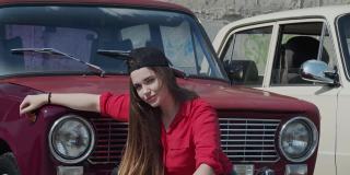 一位年轻女子以一辆旧车为背景摆好姿势