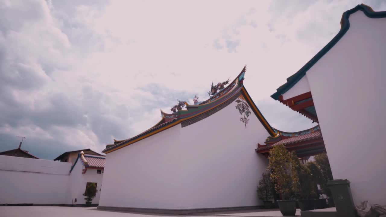 有着红色中国装饰和白色墙壁的中国寺院建筑在蓝色的天空中