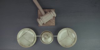 正义与法律观念。从俯视图可以看到，迈勒法官手持法庭裁决，木槌和黄铜天平放在深色的木桌上，斯劳特