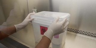 特写镜头，科学家打开微生物实验室里的空生物危害箱，准备放入危险液体和化学品。
