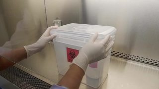 特写镜头，科学家打开微生物实验室里的空生物危害箱，准备放入危险液体和化学品。