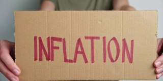 全球通胀的概念。女人拿着纸与字通货膨胀