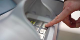 用手在自动柜员机键盘上输入密码或金额，从卡上取钱。