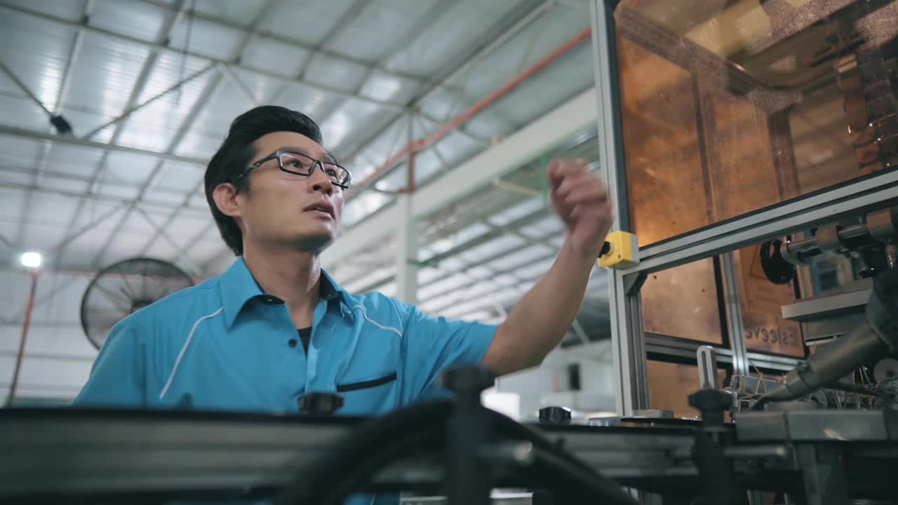 亚洲华人男性生产线工人操作贴标机在装瓶厂矿泉水饮用水厂