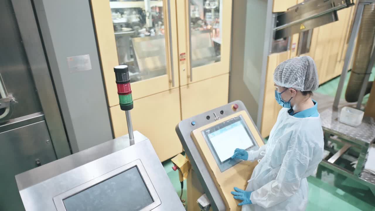 亚洲华人女生产线工人用个人防护用品操作装瓶将纯净水装瓶成瓶，瓶装水装瓶厂生产线矿泉水饮用水厂