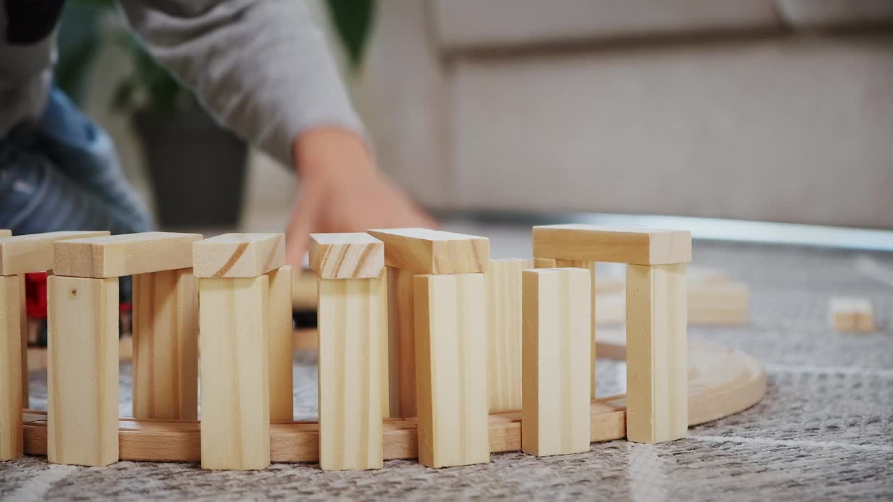 孩子们玩搭木铁路，开动电子蒸汽机车坐在家里的地板上