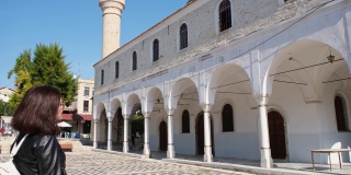 年轻的女游客来文化度假。Alacati Pazaryeri清真寺，始建于1874年，位于土耳其伊兹密尔省的Alacati度假小镇