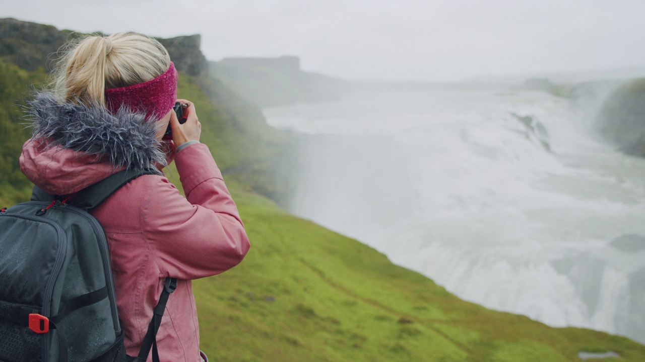 女游客在雨中拍摄令人印象深刻的Gullfoss瀑布。著名的景点和地标性的目的地在冰岛的黄金圈