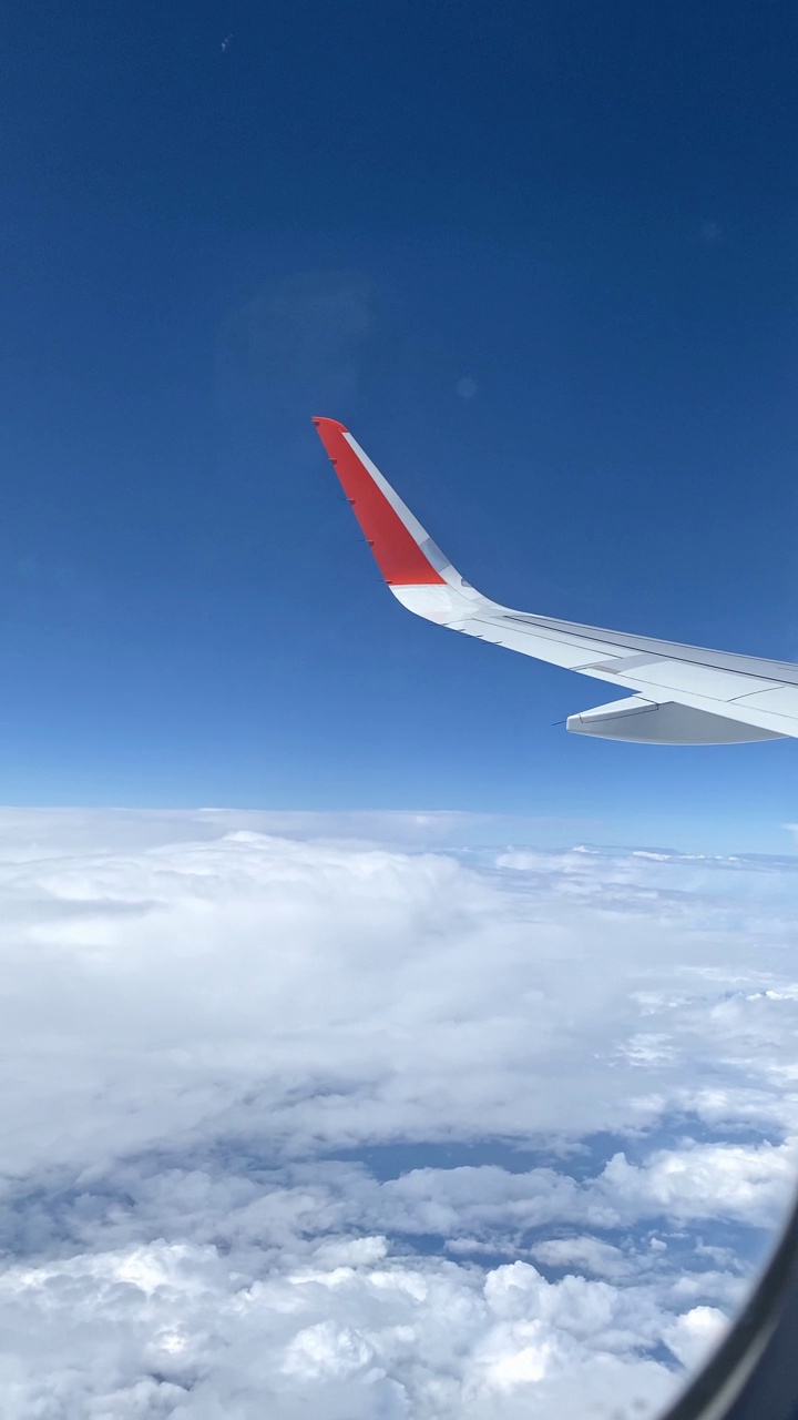 从飞机窗口看到的云朵和飞机的机翼。