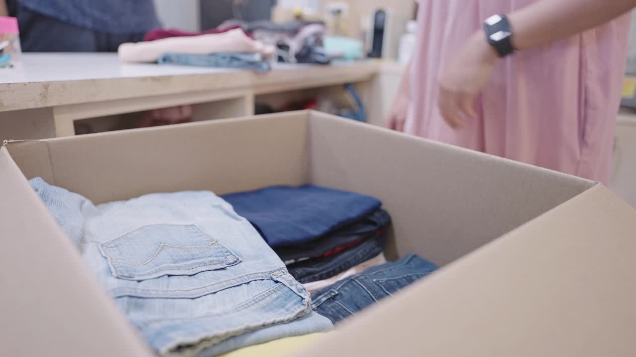 夫妇将旧衣服分拣到纸板箱中捐献