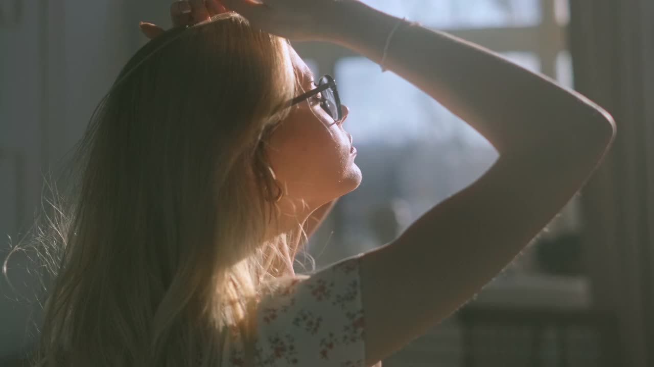 年輕迷人的白人婦女搖長金發(fā)直發(fā)在夕陽在家里。