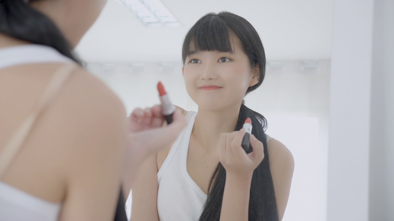 詳情圖-美麗年輕的亞洲女性涂口紅在嘴上，美麗的女孩看著鏡子的臉化妝化妝品與嘴唇的優(yōu)雅，化妝與性感的女性，皮膚護(hù)理和健康的理念。