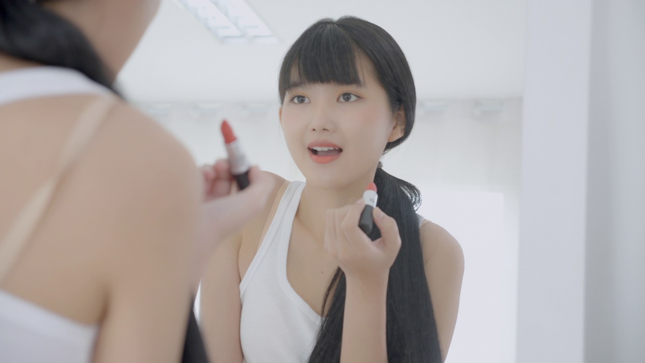 詳情圖-美麗年輕的亞洲女性涂口紅在嘴上，美麗的女孩看著鏡子的臉化妝化妝品與嘴唇的優(yōu)雅，化妝與性感的女性，皮膚護(hù)理和健康的理念。
