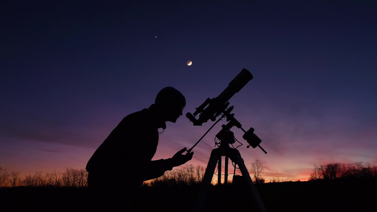 一個男人的剪影，望遠(yuǎn)鏡和夜空下的鄉(xiāng)村。