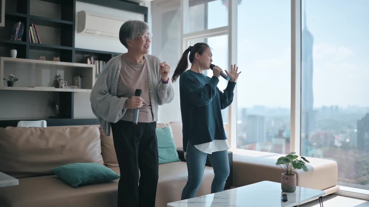 亚裔华人老太太周末与女儿在客厅唱卡拉ok跳舞