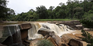 来自泰国的瀑布与岩石和树木在褐色的水。
