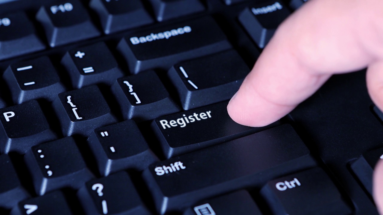 一个男性的手按下计算机按钮上的注册按钮的特写