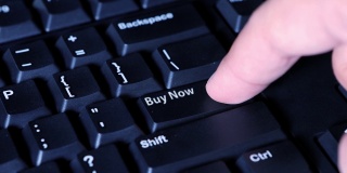 人体手指按下电脑键盘上的“现在买”按钮的特写