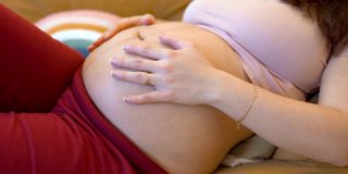 一位孕妇坐在客厅的沙发上，轻轻地抚摸着自己的大肚子