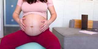孕妇在家中客厅里的健身球上进行分娩前的肌肉锻炼