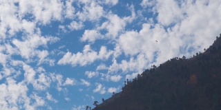 在印度喜马偕尔邦的马纳里，一群游客乘坐降落伞在山上的云朵前滑翔。游客们从山上起飞体验滑翔伞。