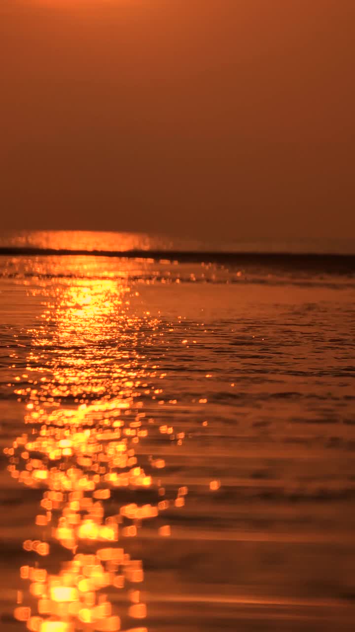 倾斜拍摄的落日在海滩的反射_4k_v