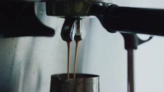 浓缩咖啡机正在煮新鲜的咖啡。将咖啡从机器中倒入钢杯中。咖啡壶里的浓缩咖啡。酿造。美味的咖啡。咖啡因