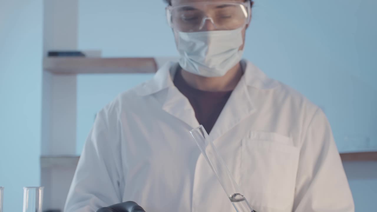 医生穿着晨衣，戴着防护橡胶手套，戴着护目镜，在近距离观察瓶中的液体是否有异味。科学实验室的研究工作。