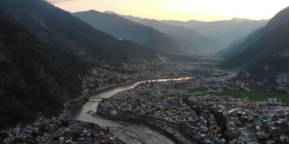 在印度北阿坎德邦的丘陵景观上的喜马拉雅城市鸟瞰图，山上有一条河流流过。无人机的观点。