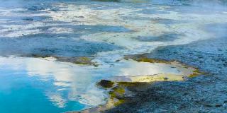 黄石国家公园，蒙大拿州，2021年7月。空中特写无人机视图的水向下流动，从一个热水池通过狭窄的岩石通道硫磺覆盖的岩石