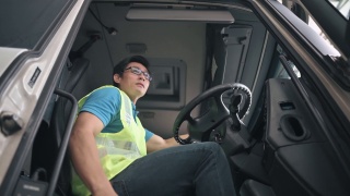亚洲华人半挂车司机正准备送他的货到驾驶座上
