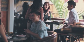 在酒吧的欢乐时光里，亚裔印度女服务员用数码平板电脑为顾客点餐