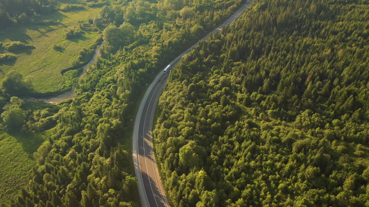 从鸟瞰的角度拍摄一条穿过树林的蜿蜒道路。