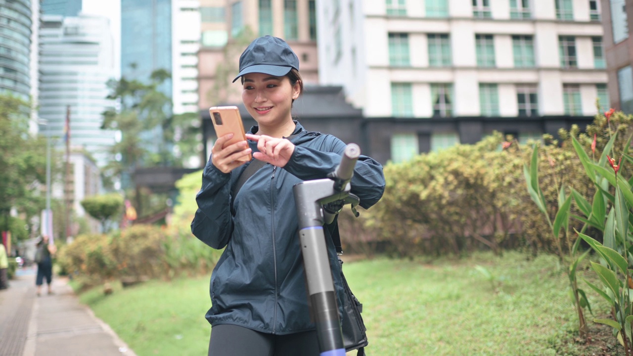 亚洲华人女性送货员在城市中以电动滑板车为交通工具的移动中查看订单地址