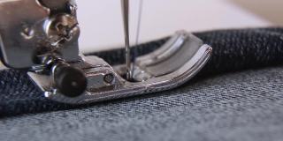 一台近距离缝纫机缝蓝色牛仔布。缝纫机的针在动