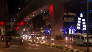印度尼西亚雅加达市中心，夜间拥挤的道路上有汽车、摩托车和人群
