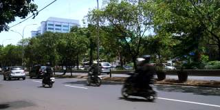 印度尼西亚雅加达市中心，绿色的树木和汽车、摩托车在道路上