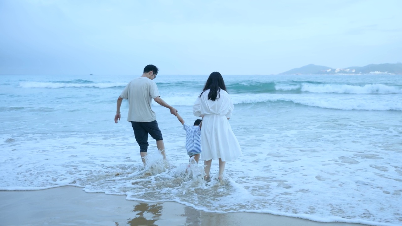 亚洲父亲，母亲和儿子走到海边的海滩上