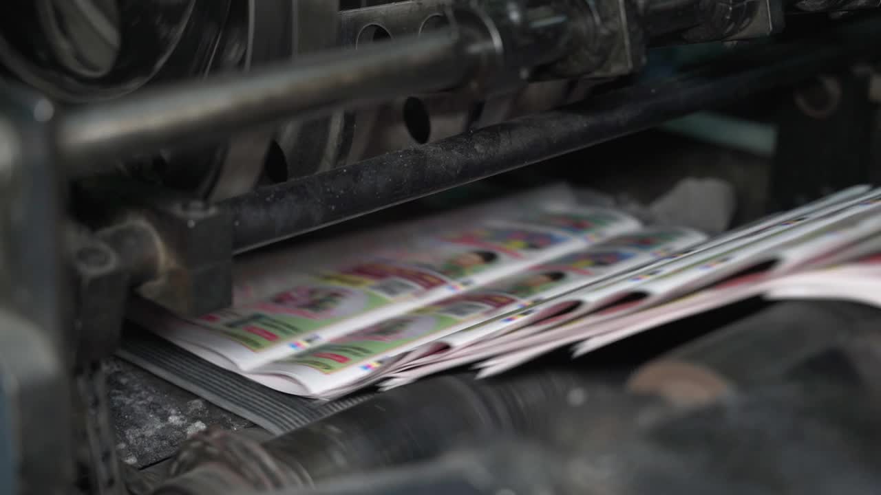 印刷的报纸沿着传送带移动。印刷的房子。印刷出版物、报纸落在传送带上并沿传送带移动。媒体，文章，每日新闻，印刷版，新闻，政治