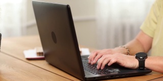 男人在笔记本电脑上打字，在家里或办公室的电脑上工作