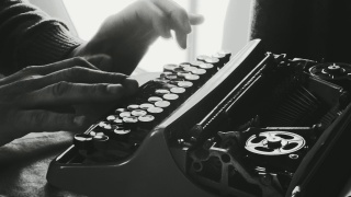 男人的手使用老式打字机，浅景深和背光。写书或者电影剧本。画廊里的大范围打字机镜头