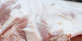 在肉类加工厂，屠夫正在用刀切生猪肉