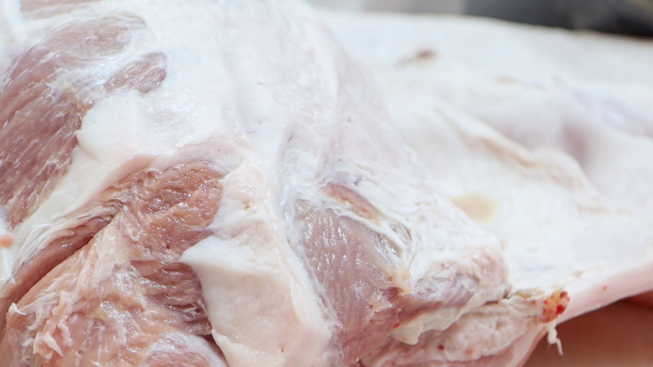 在肉类加工厂，屠夫正在用刀切生猪肉