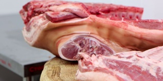 在肉类加工厂，屠夫用锋利的斧头劈生猪肉。