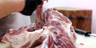 屠夫在肉类加工厂从猪肉身上切骨头。